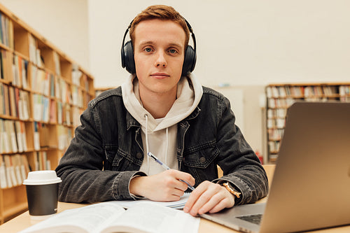 Handsome male student in a university library. Young man studying on school assignment.