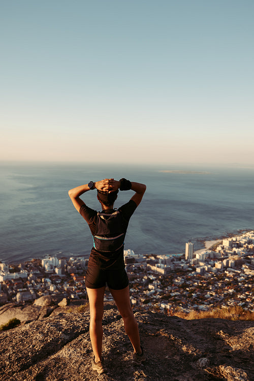 Rear view of woman standing on the edge. Female relaxing after hike enjoying the view.