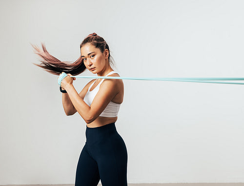 Fitness woman exercising with resistance band looking at camera