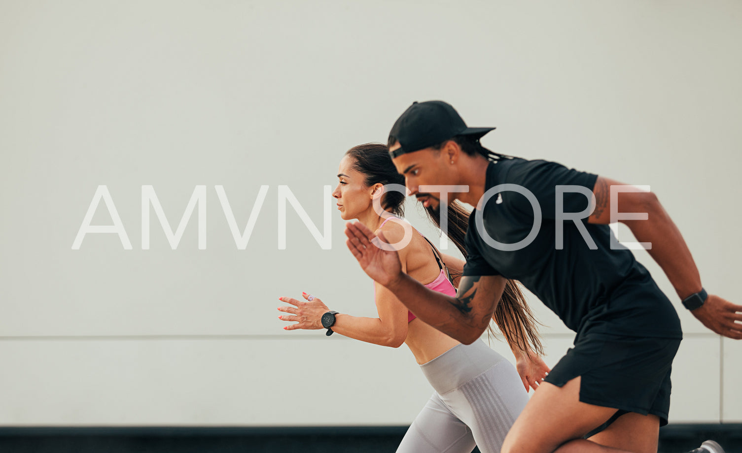 Side view of male and female runner exercising together at the wall