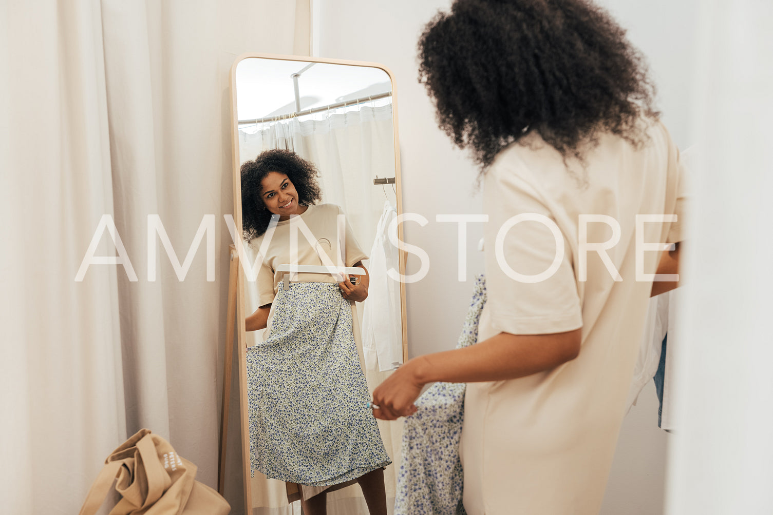 Stylish woman trying on clothes in a dressing room in a boutique