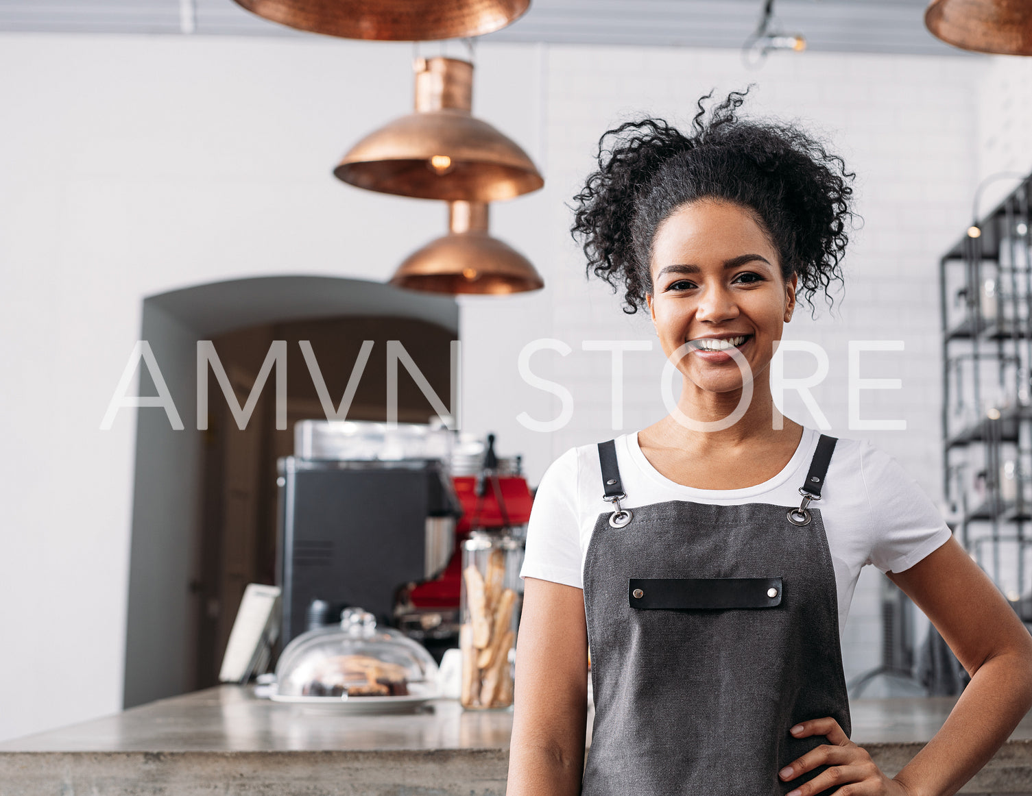 Smiling and confident barista looking at camera while standing in coffee shop