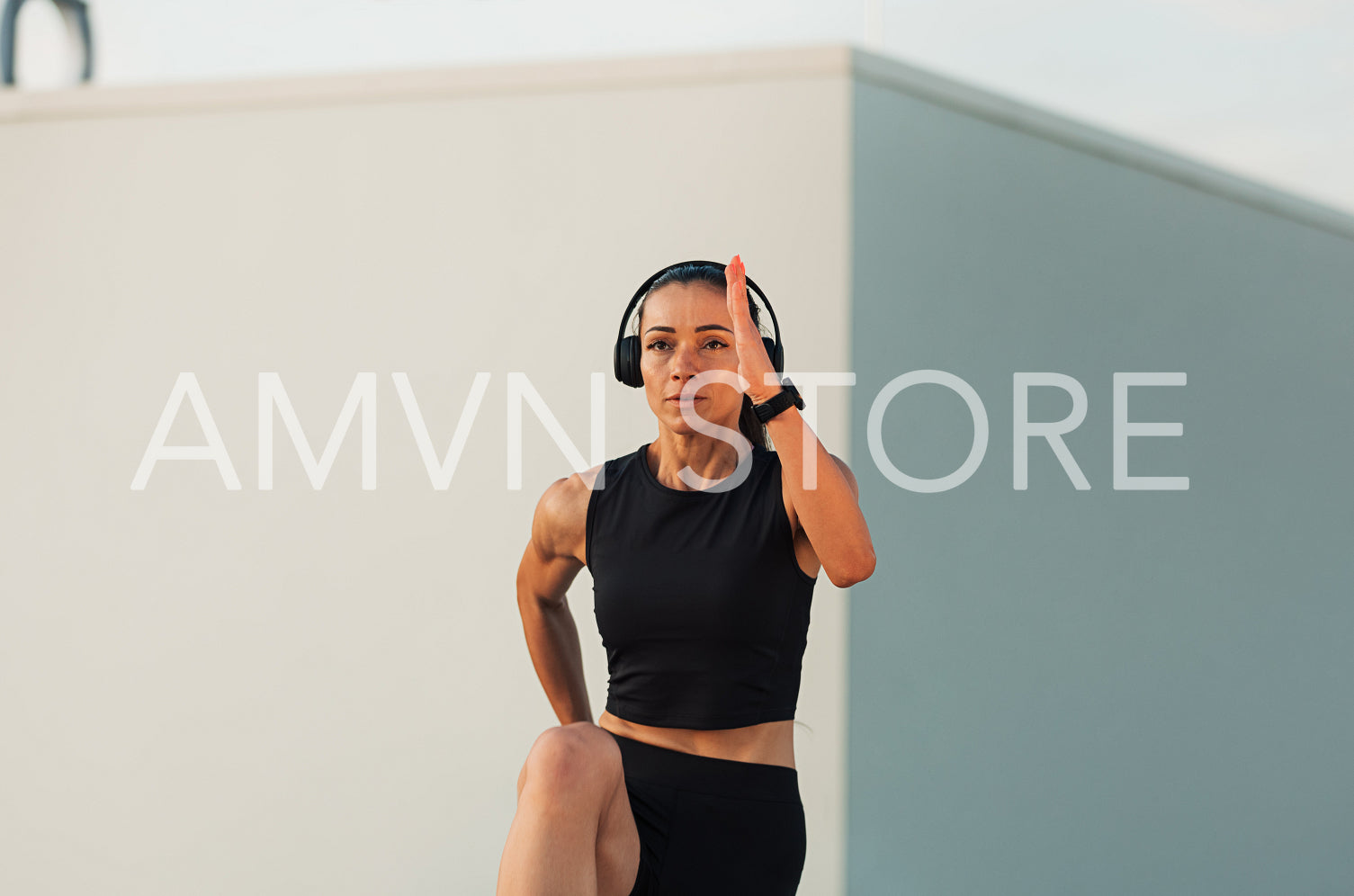 Young slim woman wearing headphones doing warming up exercises