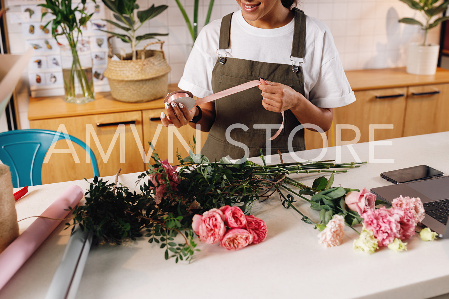 Cropped image of unrecognizable florist woman holding a ribbon at counter	