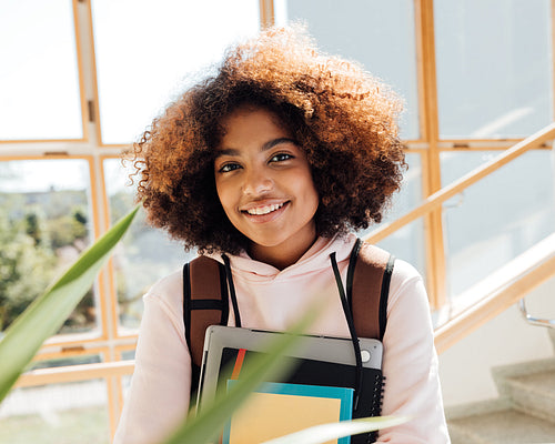 Portrait of a beautiful smiling girl with curly hair standing in high school