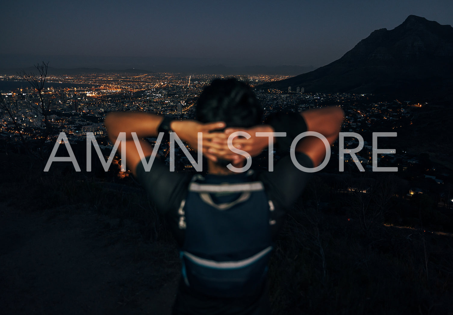 Unrecognizable woman hiker enjoying the view of a night city from mountain