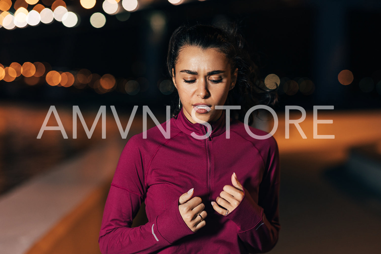 Sportswoman warming up before training. Young female with closed eyes exercising outdoors.