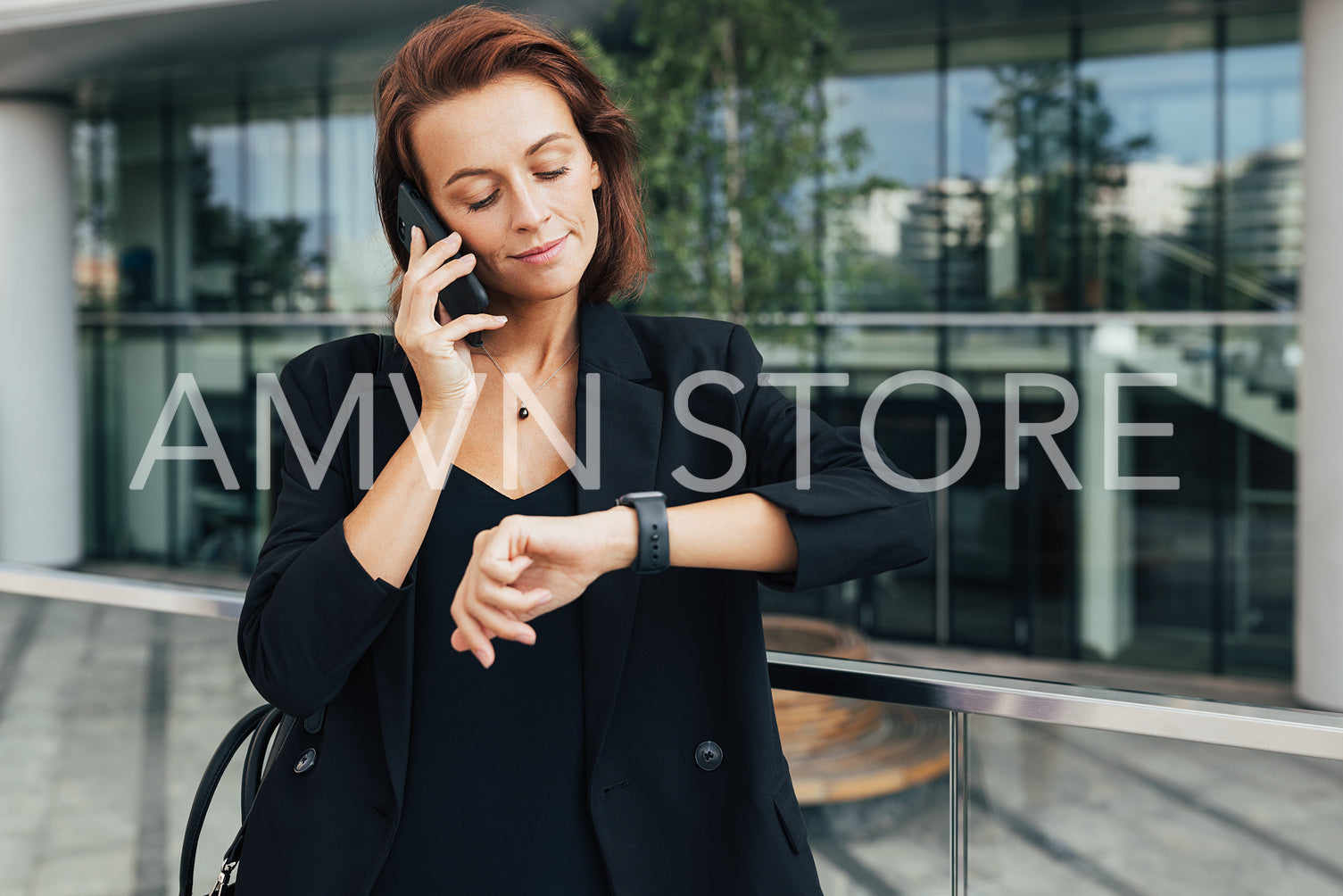 Middle-aged businesswoman looking at her smartwatch while talking on mobile phone