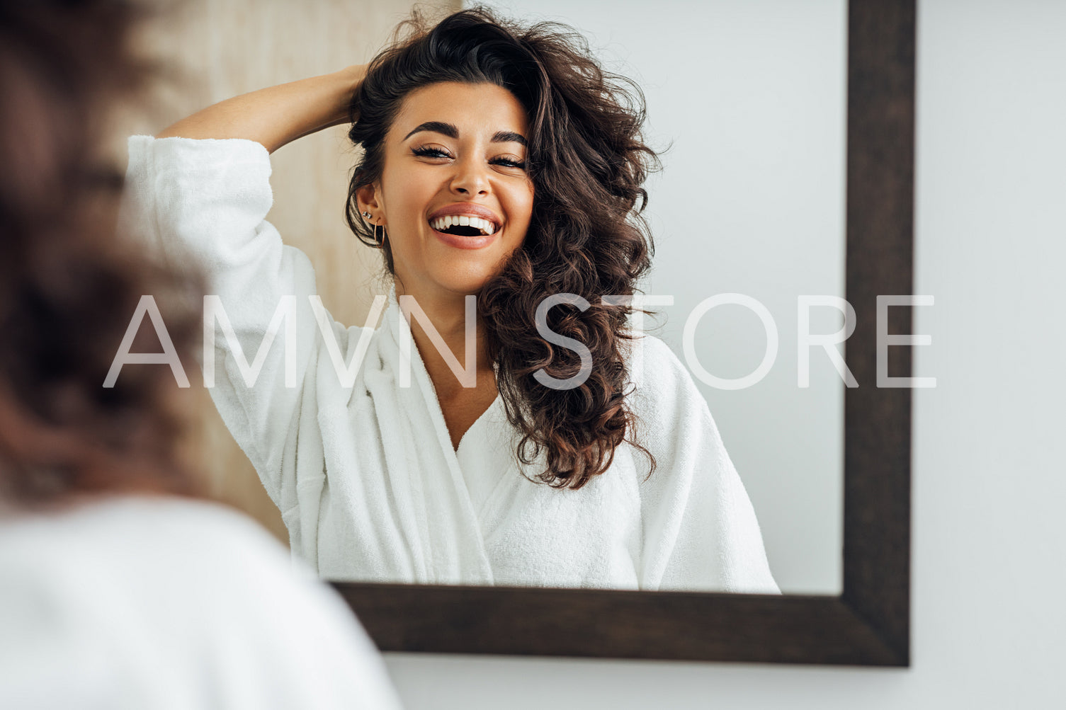 Happy woman in bathroom. Young female playing with her hair in front of a mirror.	