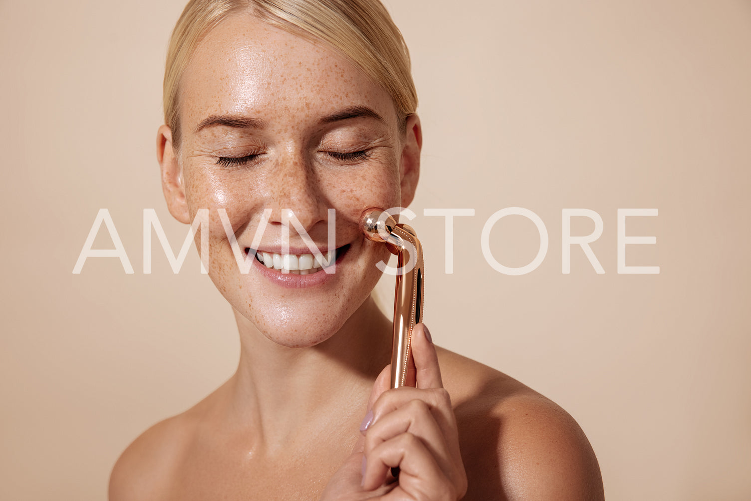 Happy woman using facial roller. Young female doing skincare routine.