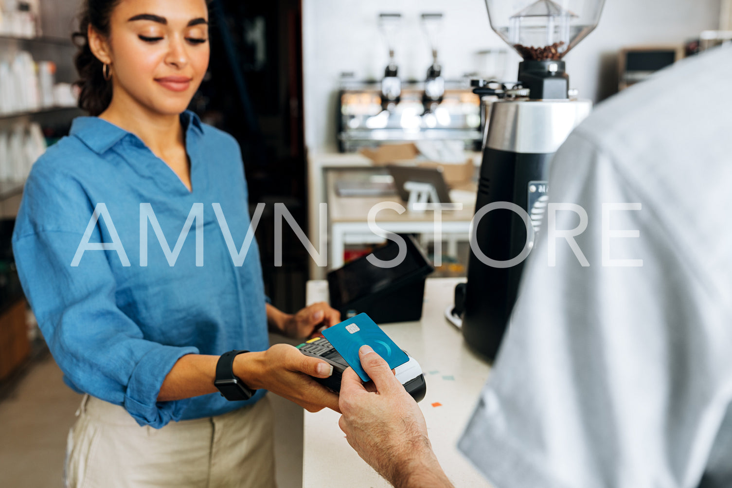 Female coffee shop owner holding a POS terminal while unrecognizable customer paying cashless	