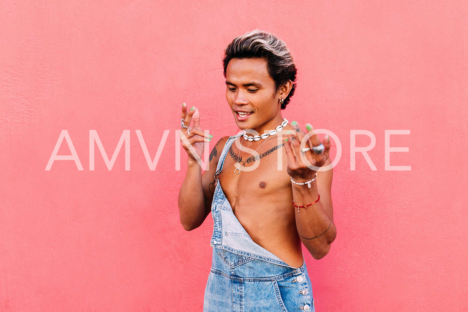 Stylish guy in denim dancing outdoors against pink wall