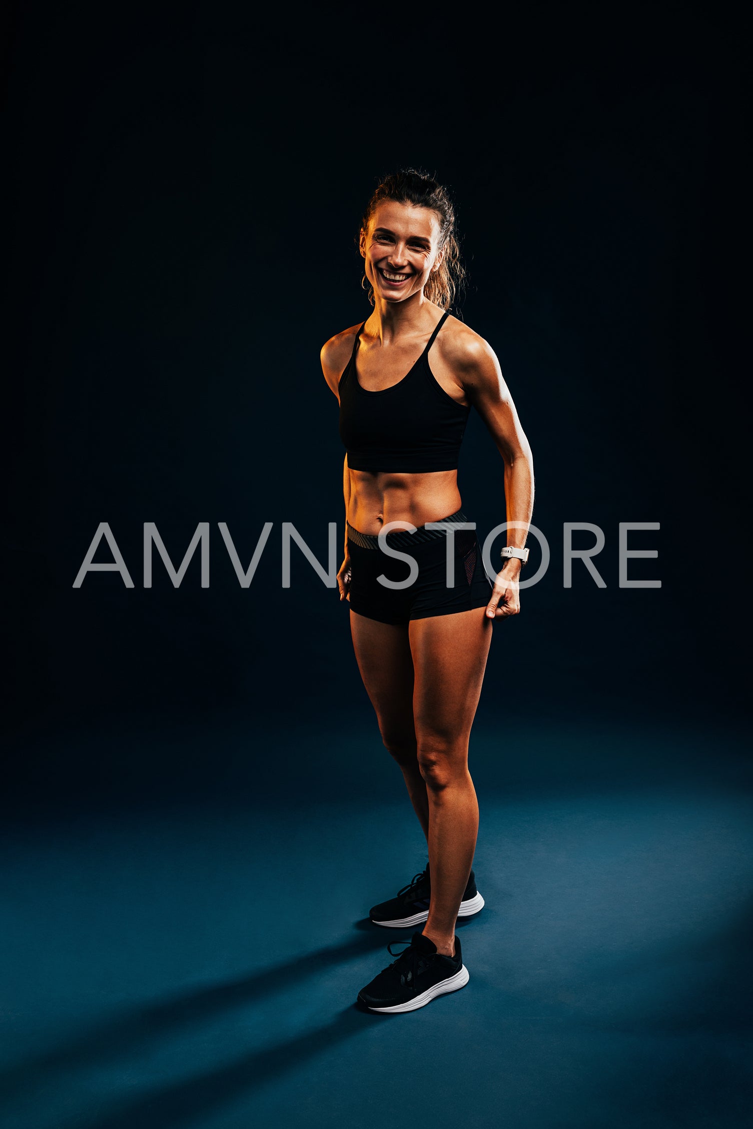 Young fit runner in sportswear standing on dark background in studio and looking at camera