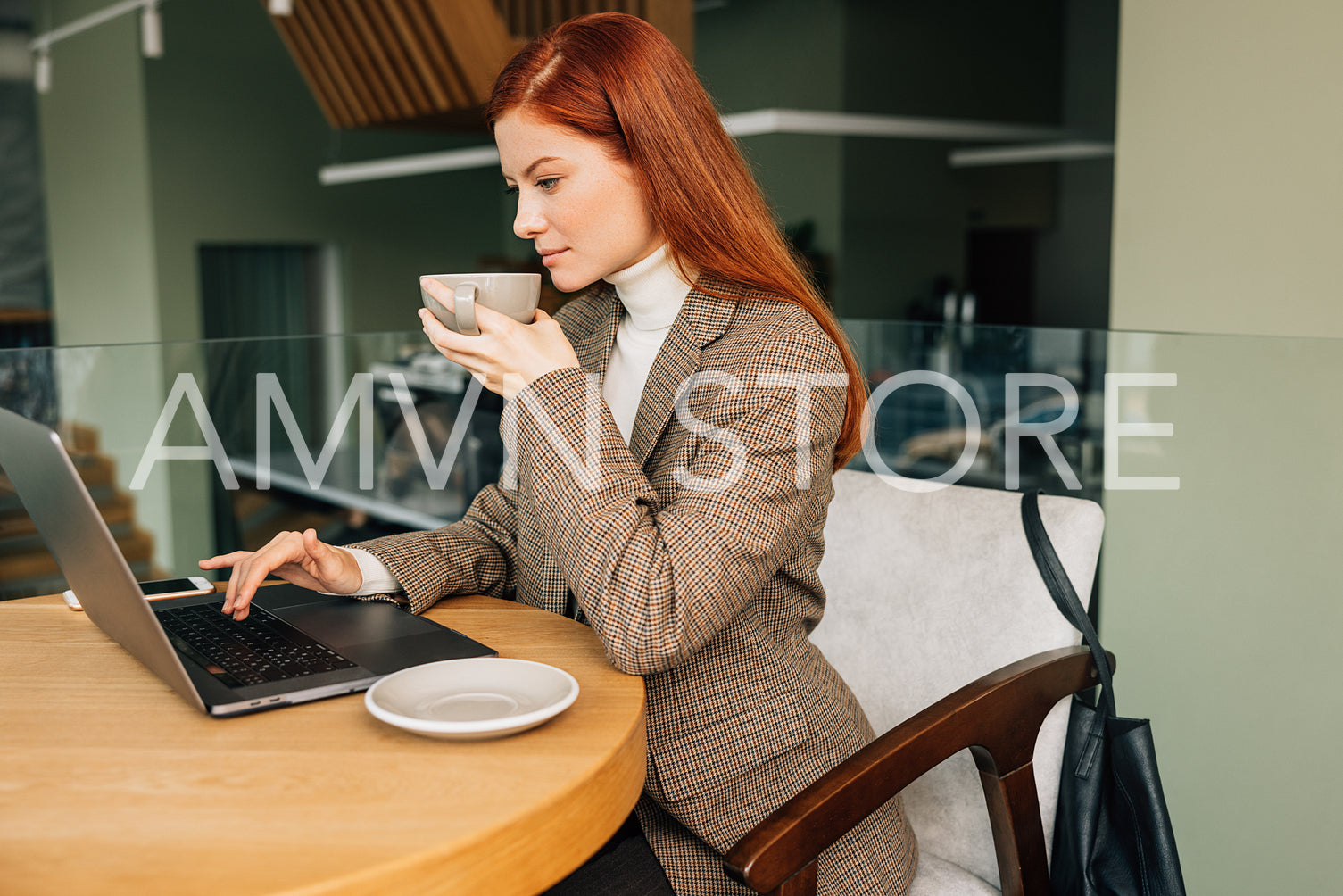 Businesswoman in formal wear typing on laptop in cafe. Young female drinks coffee and work remotely.