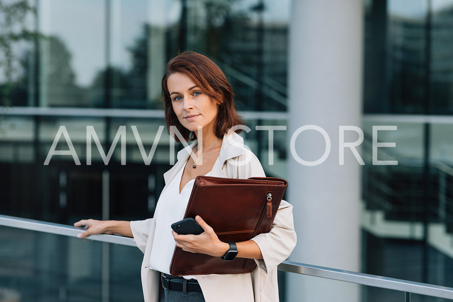 Confident business woman with ginger hair looking at camera. Middle-aged female with folder at business building.