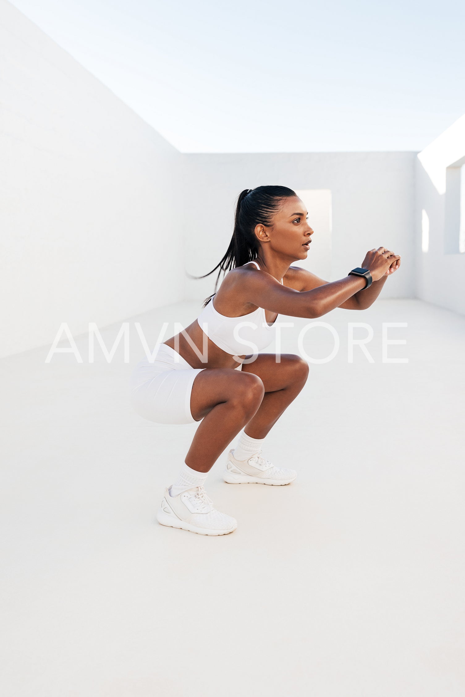 Slim woman practicing sit-ups in the white outdoor studio. Fitness female doing exercises for legs and glutes.