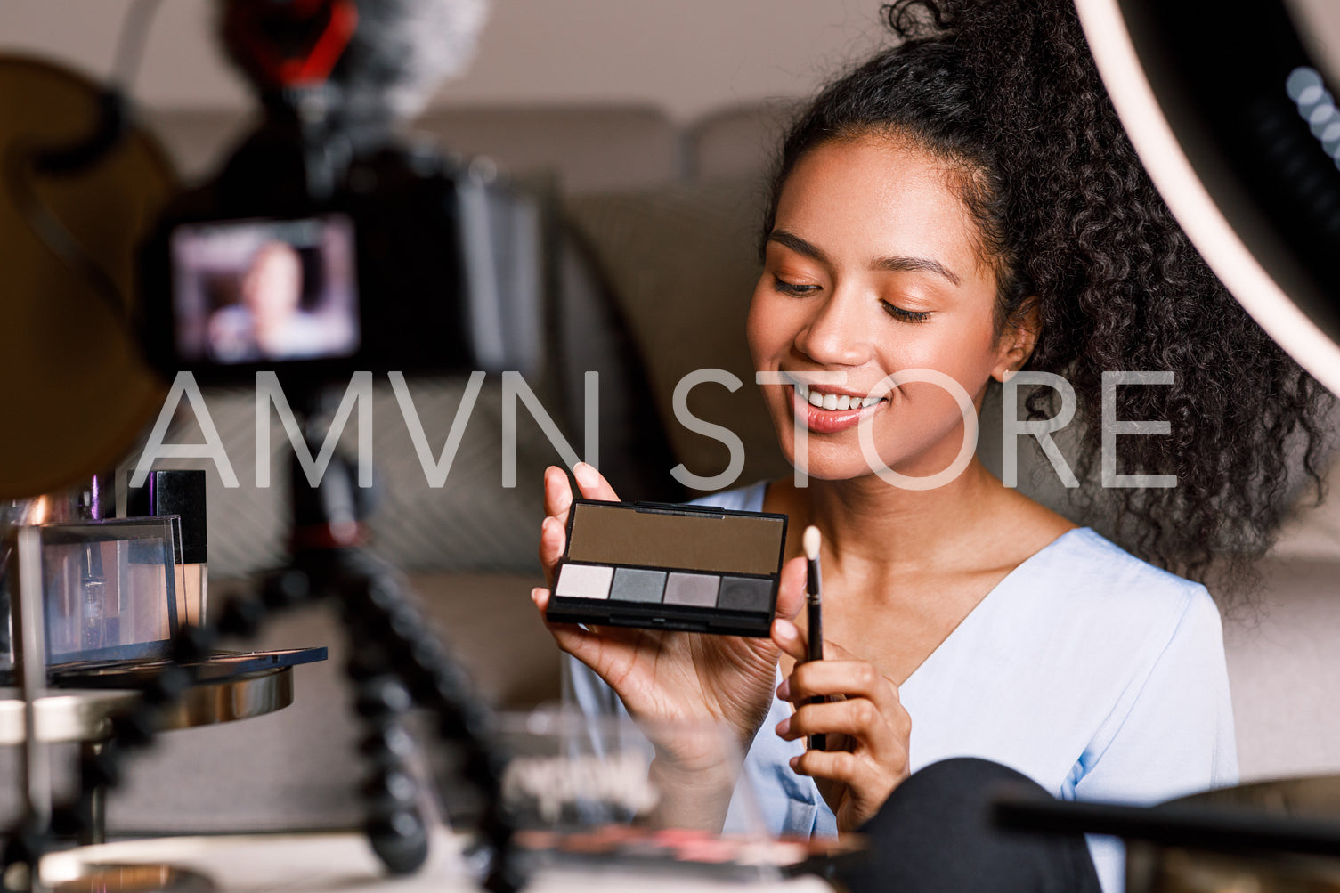 Smiling influencer making a review on eyeshadow palette while sitting in front of a camera