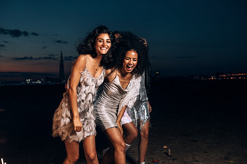 Laughing friends walking together at night outdoors looking at camera