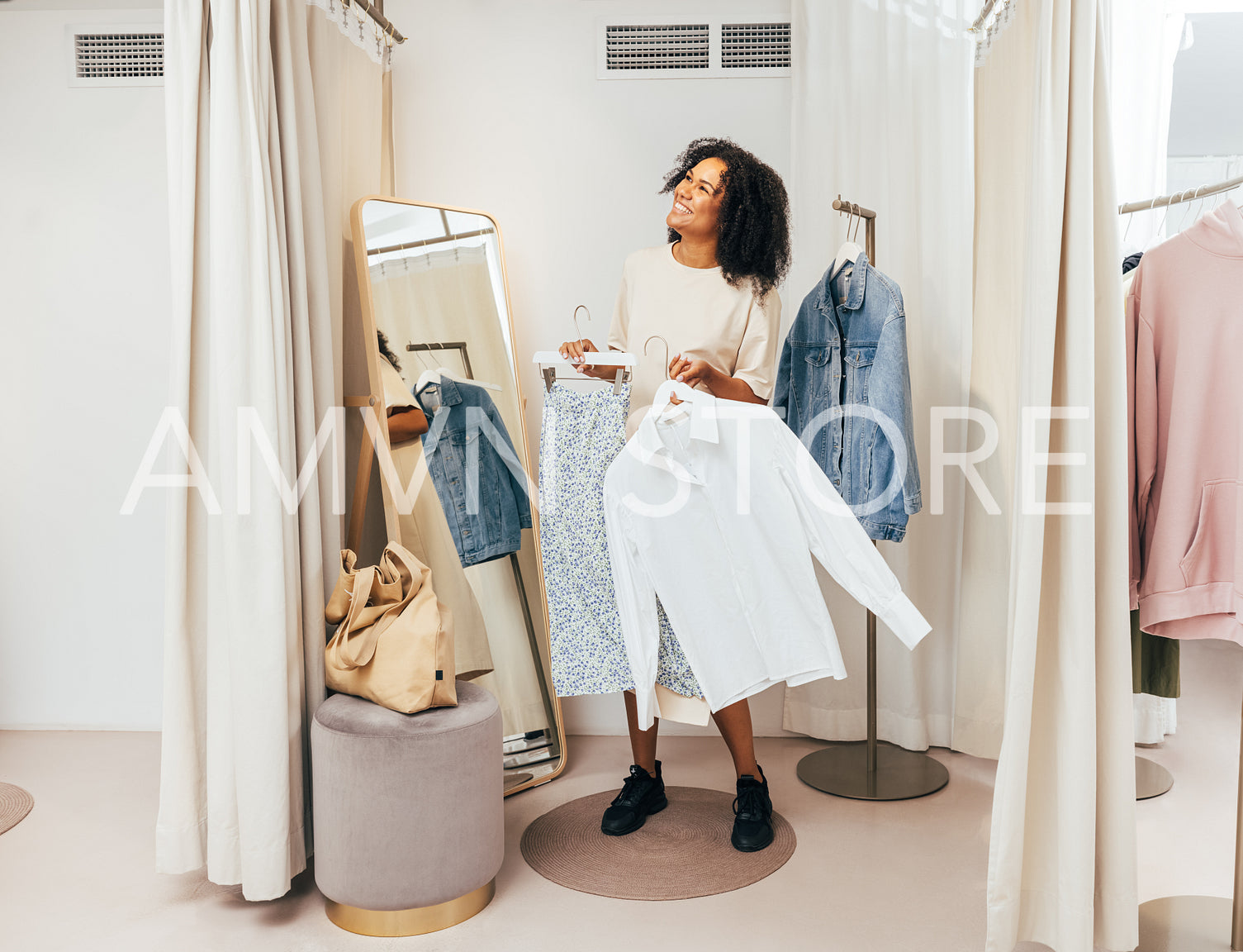 Smiling woman with clothes on hangers having fun in a dressing room