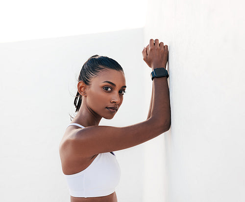 Slim athlete leaning white wall looking at the camera