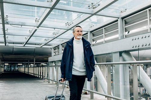 Handsome mature man walking with his luggage at airport