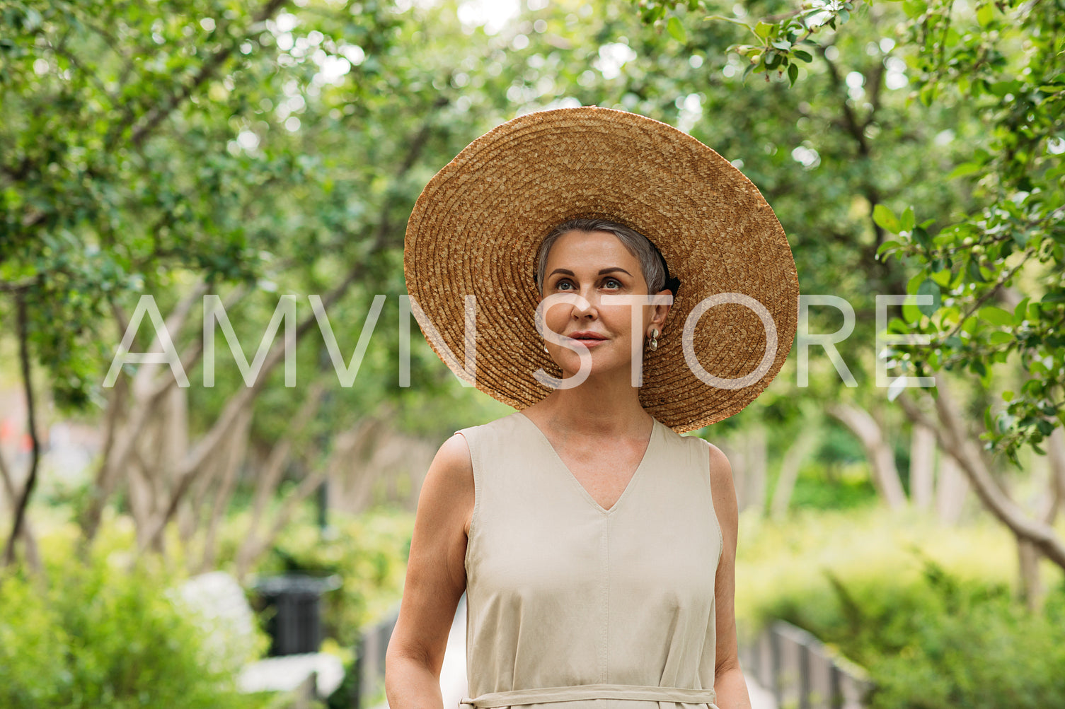 Senior woman wearing big straw hat walking in park 