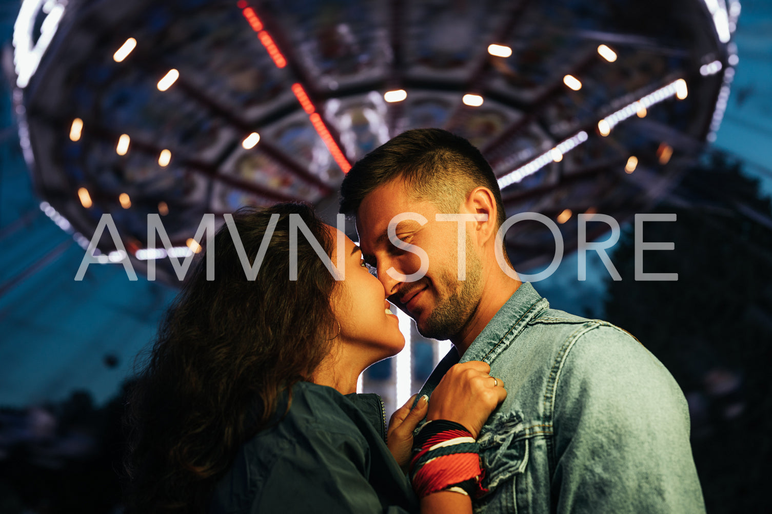 Young couple standing face to face at night in amusement park