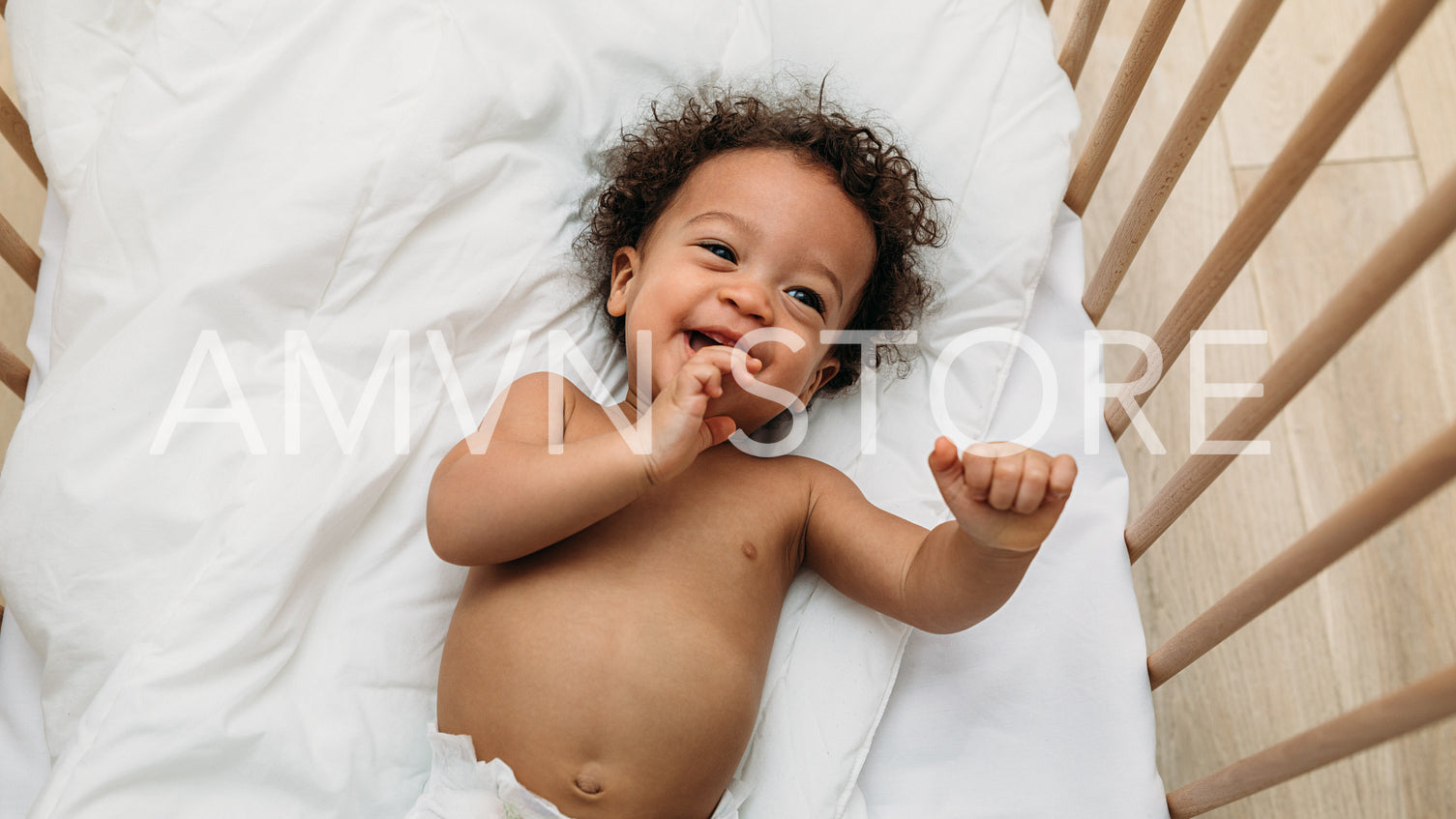 Laughing baby boy lying down on a bed	