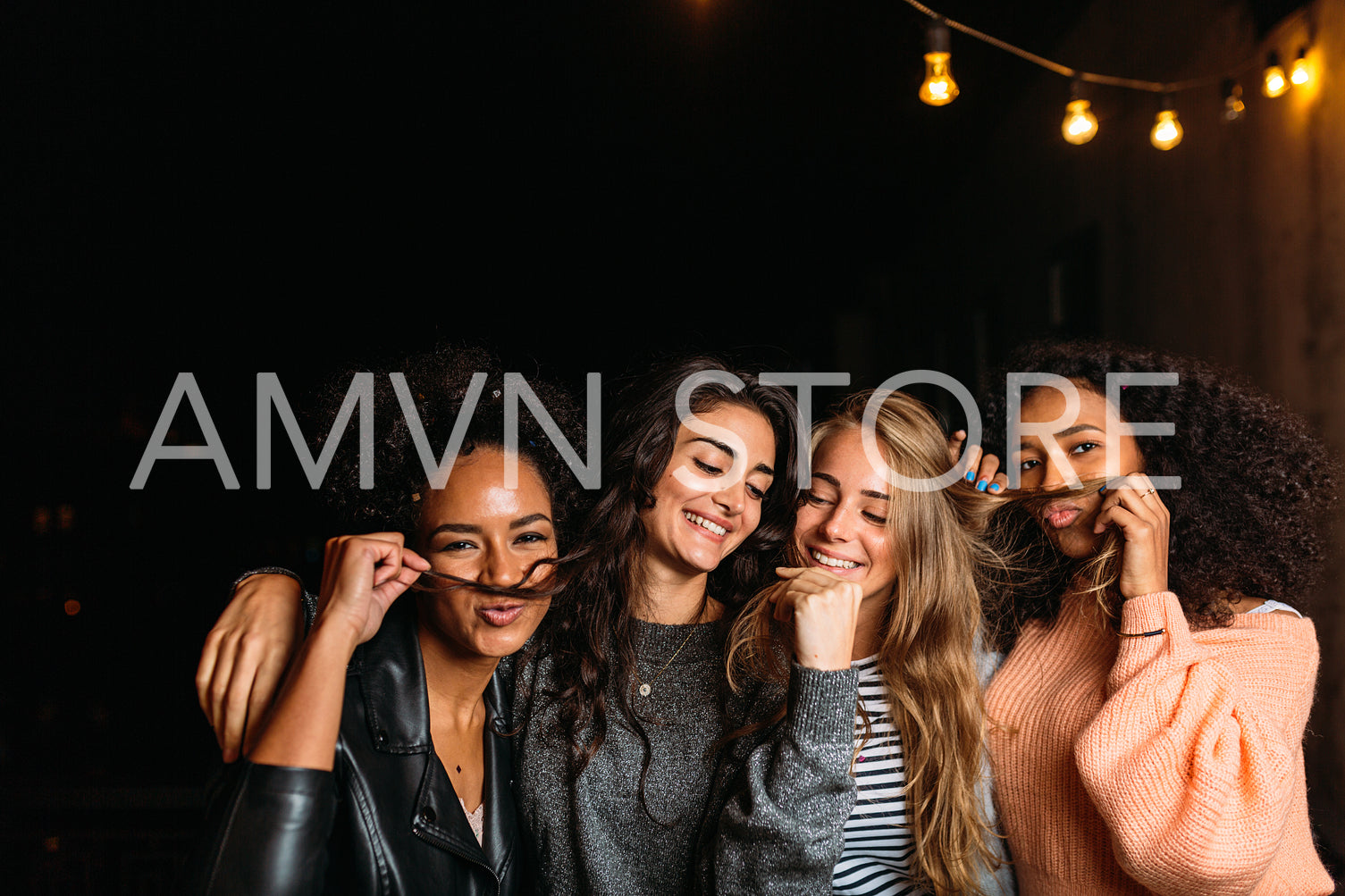 Night shot of young women making mustaches with hair	