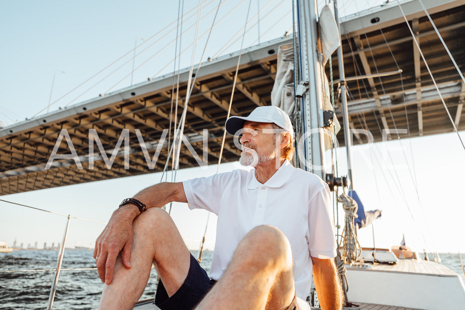 Mature man looking away while sitting on his sailboat	