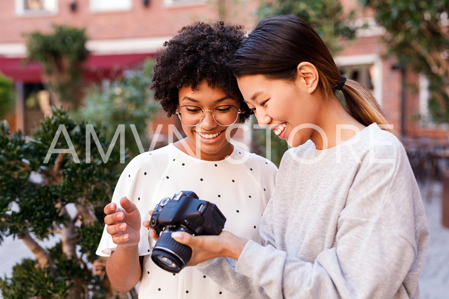 Smiling blogger and her photographer looking at digital camera after shooting	