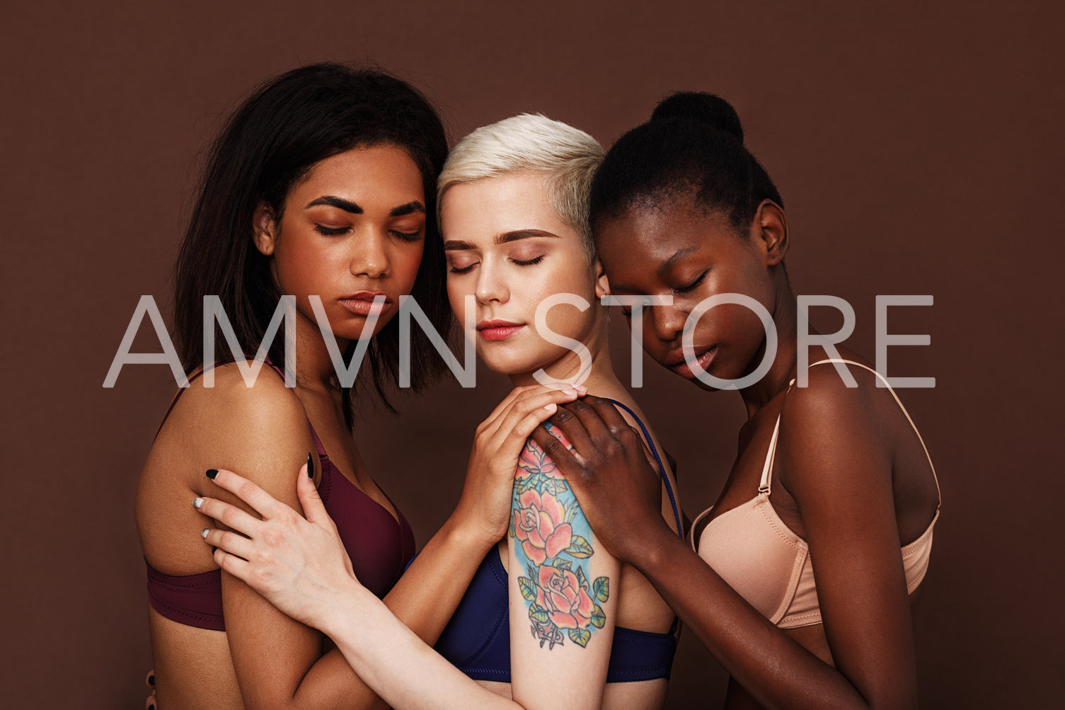 Three diverse women in bras standing with closed eyes over brown