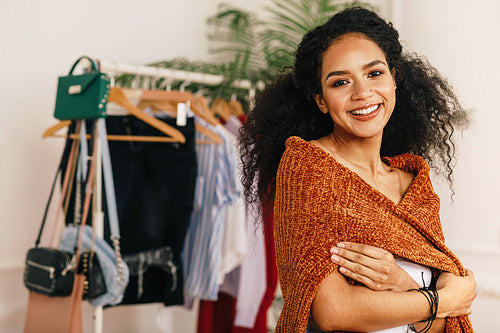 Portrait of a beautiful woman with curly hair standing at clothes rack