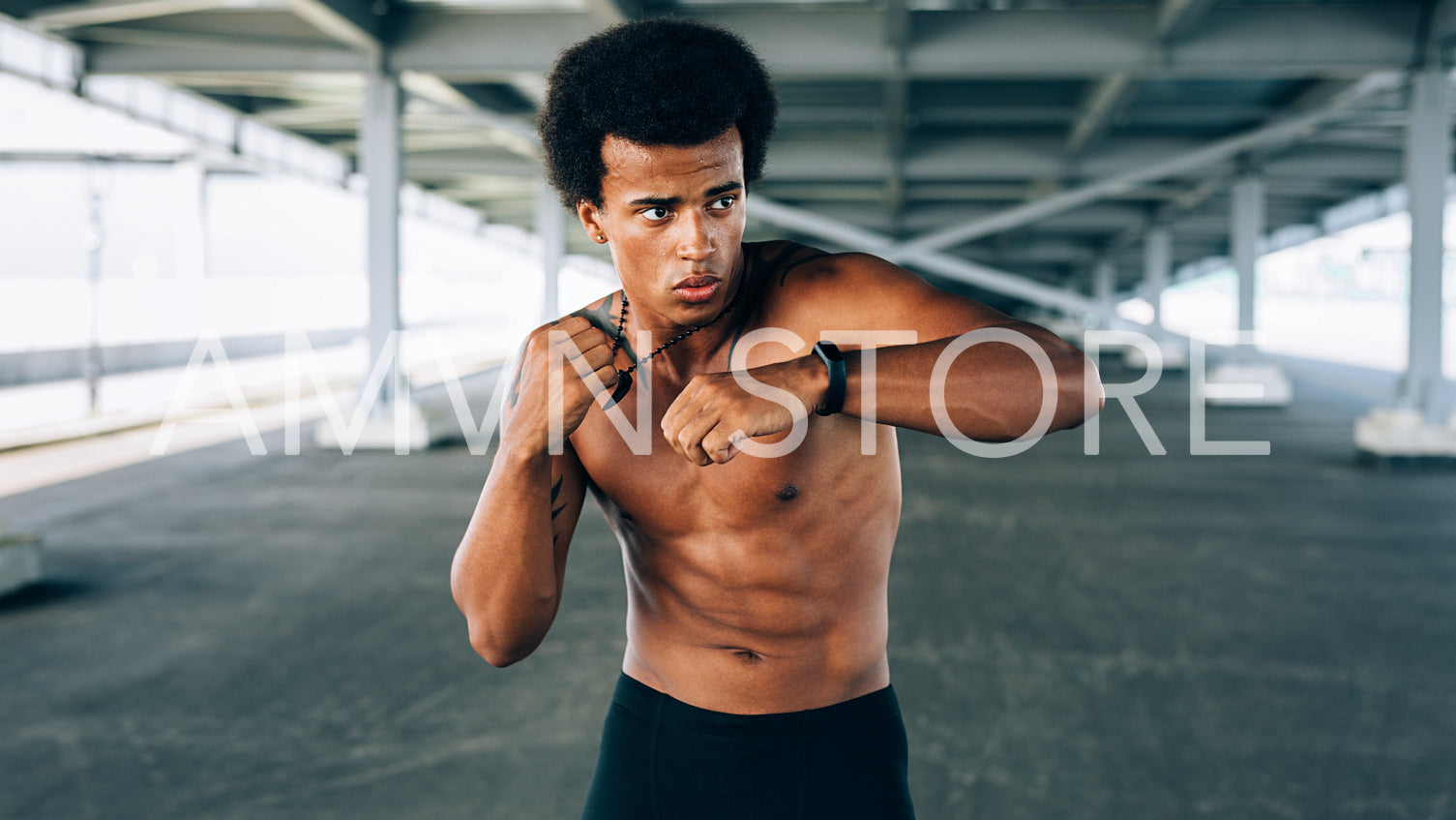 Young sportsman warming up under a bridge, doing boxing exercises	