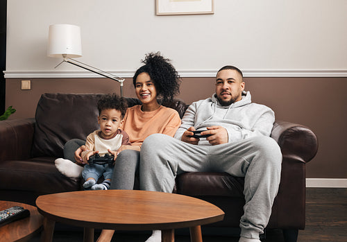 Mother, father, and little son spending time together at home playing video games