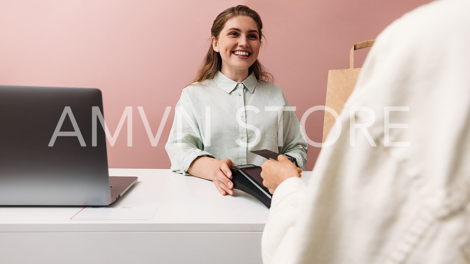 Happy clothing store owner looks at the buyer while he pays with