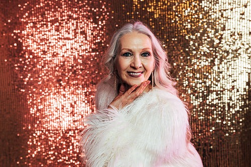 Portrait of a mature woman posing in studio wearing fur coat loo