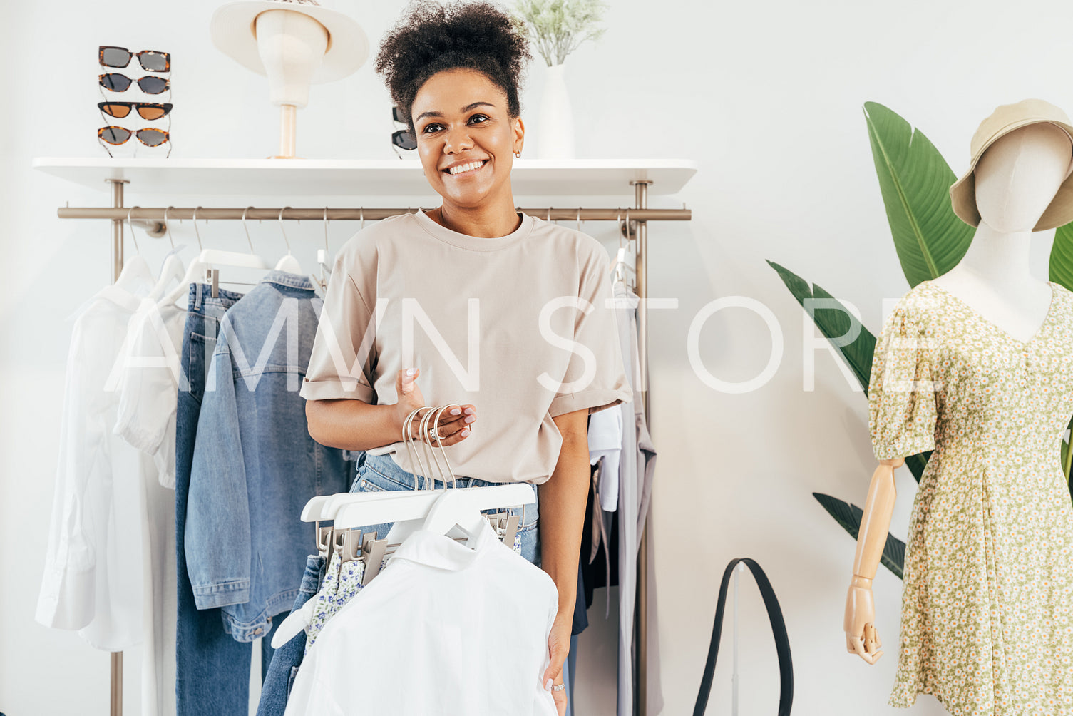 Cheerful woman working in clothing store holding a bunch of hangers