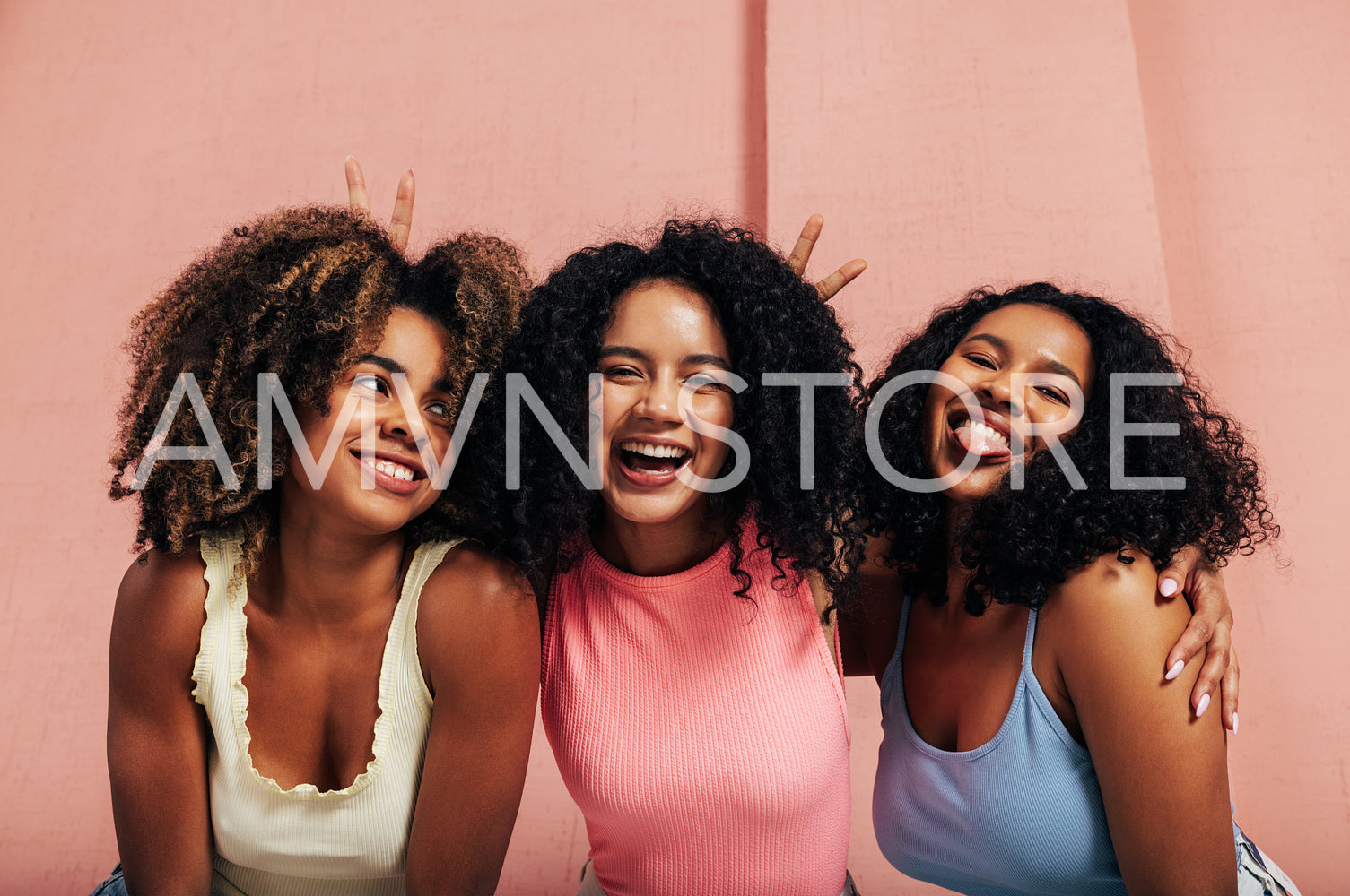 Portrait of three laughing females with curly hair. Happy women having fun together looking at camera.