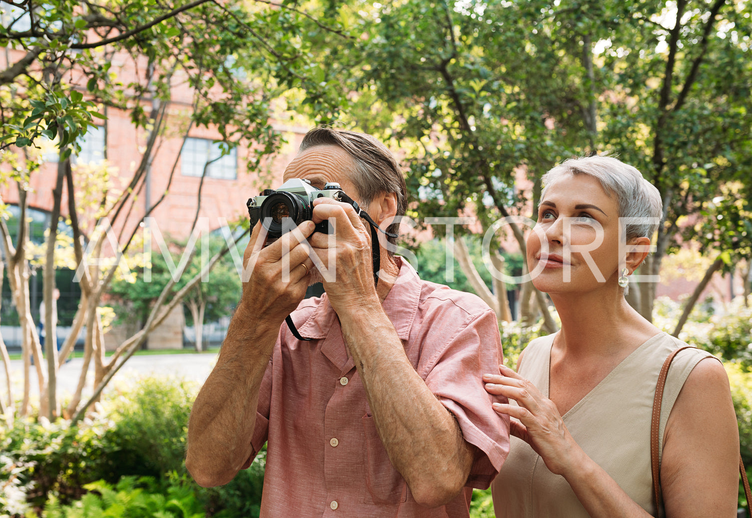 Aged tourist in the park. Senior male making photographs on a film camera.