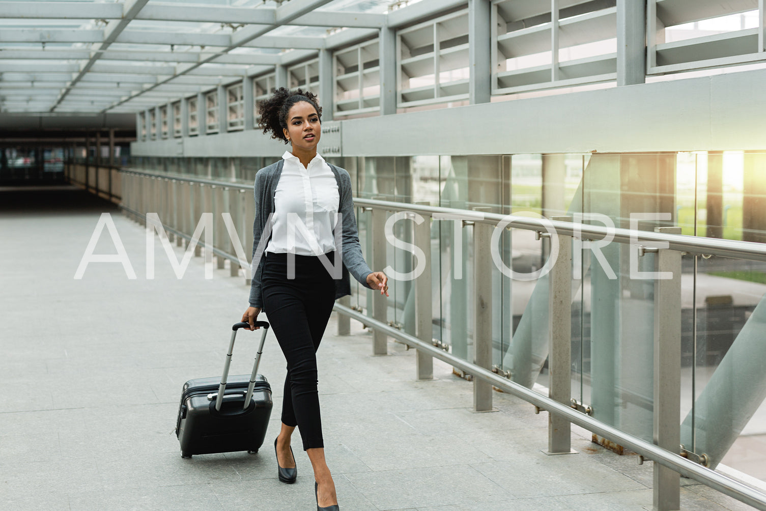 Beautiful businesswoman walking inside public transportation station with suitcase, front view	