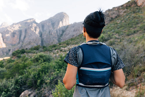 Rear view of woman hiker in sportswear standing in the valley an