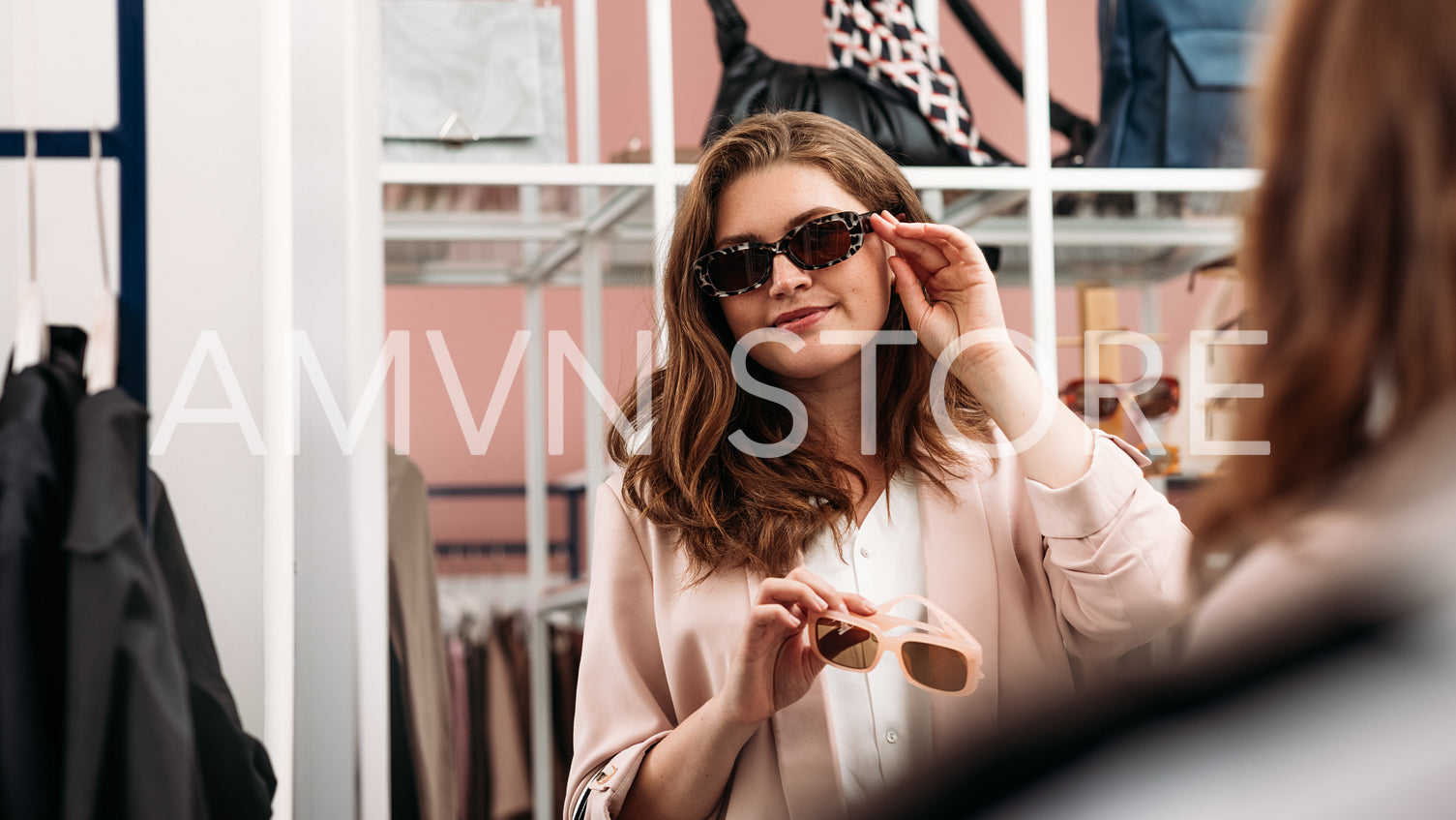 Smiling woman trying fashionable sunglasses in front of a mirror