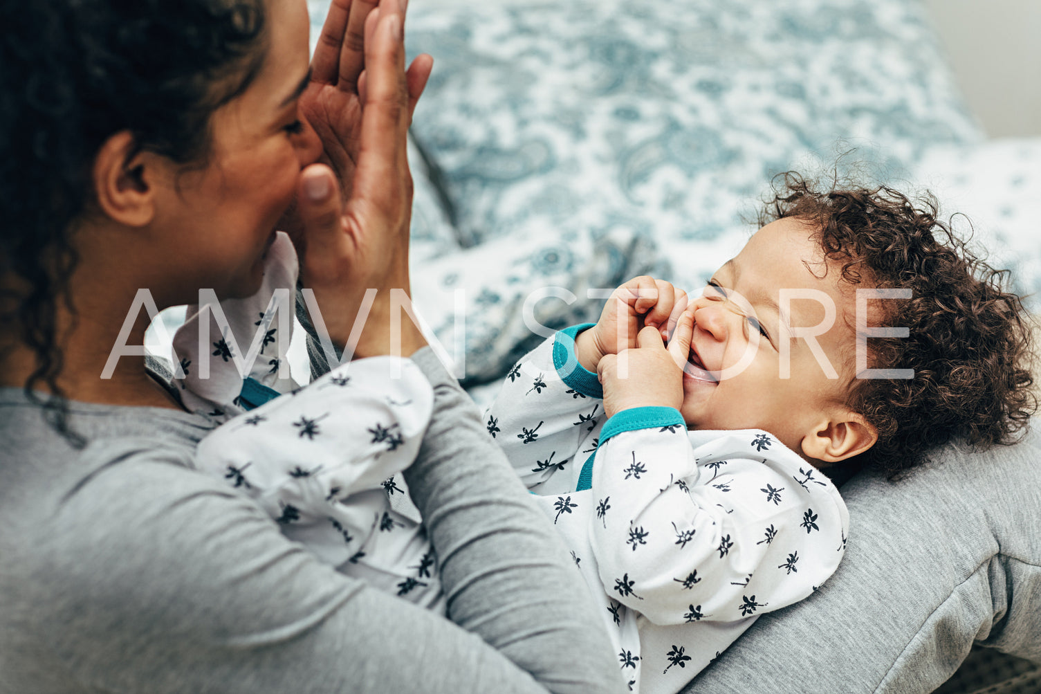 Happy baby boy lying on mother legs while she playing with him	