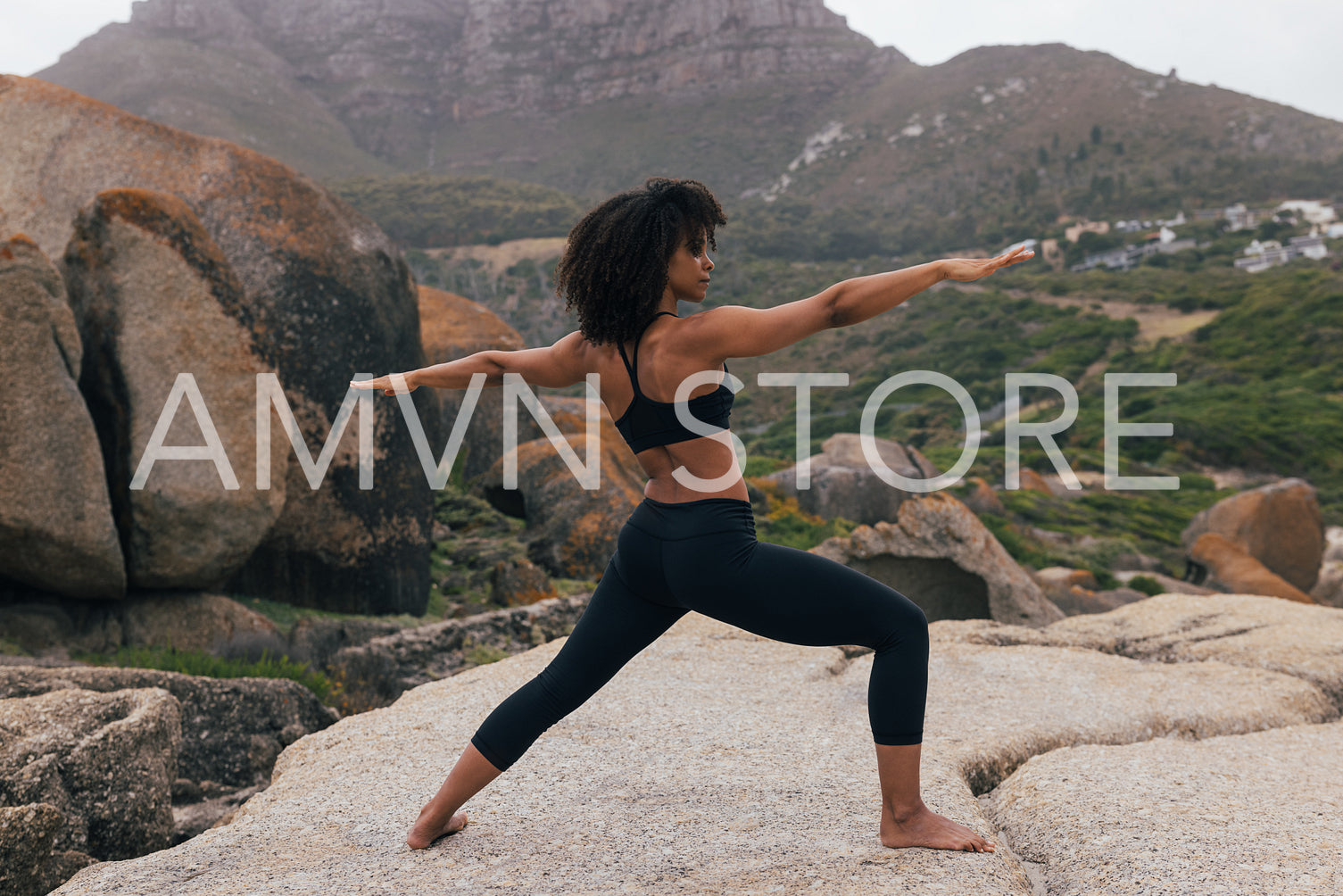 Full length of young woman doing warrior pose against beautiful landscape at sunset