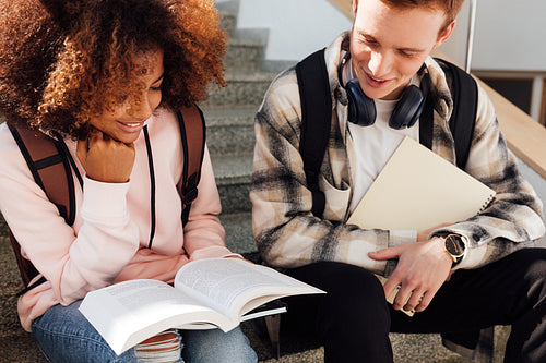 College students reading a book while sitting on a stairs