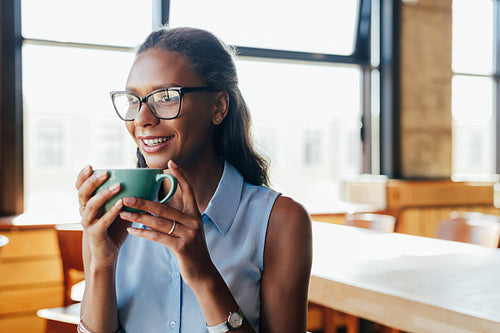 Portrait of young woman wearing glasses holding a cup of coffee