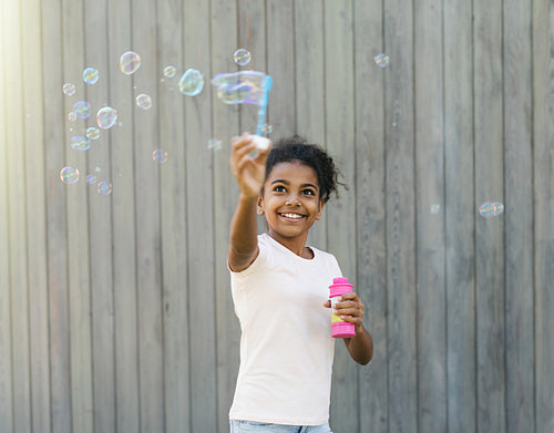 Happy girl in park making soap bubbles