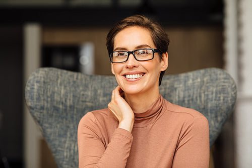 Close up portrait of a beautiful businesswoman sitting on an armchair in apartment