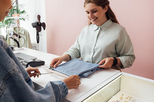 Unrecognizable customer buying clothes from a saleswoman at a fa